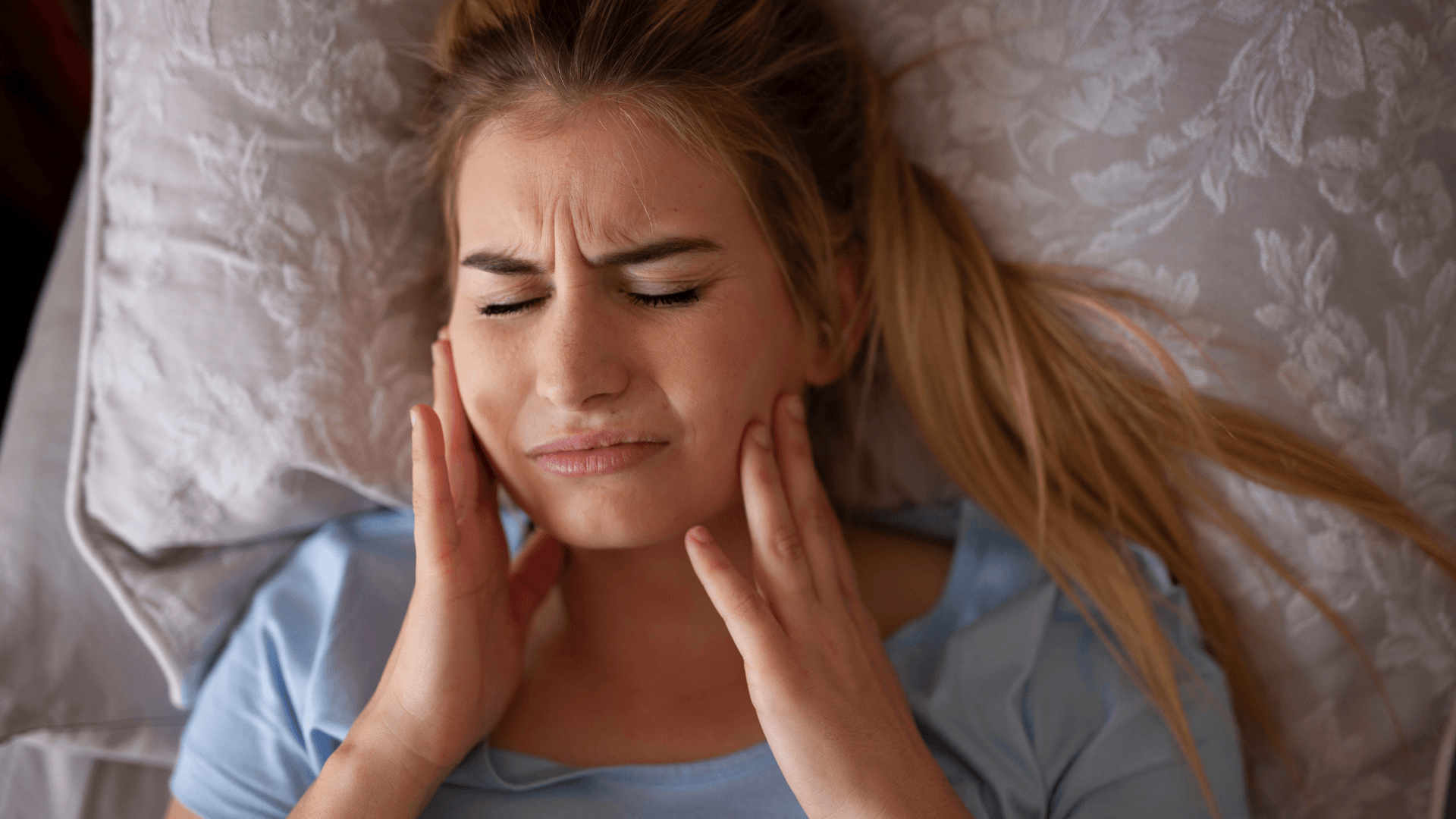 Mujer con dolor mandibular y tensión facial al despertar por bruxismo nocturno en Madrid